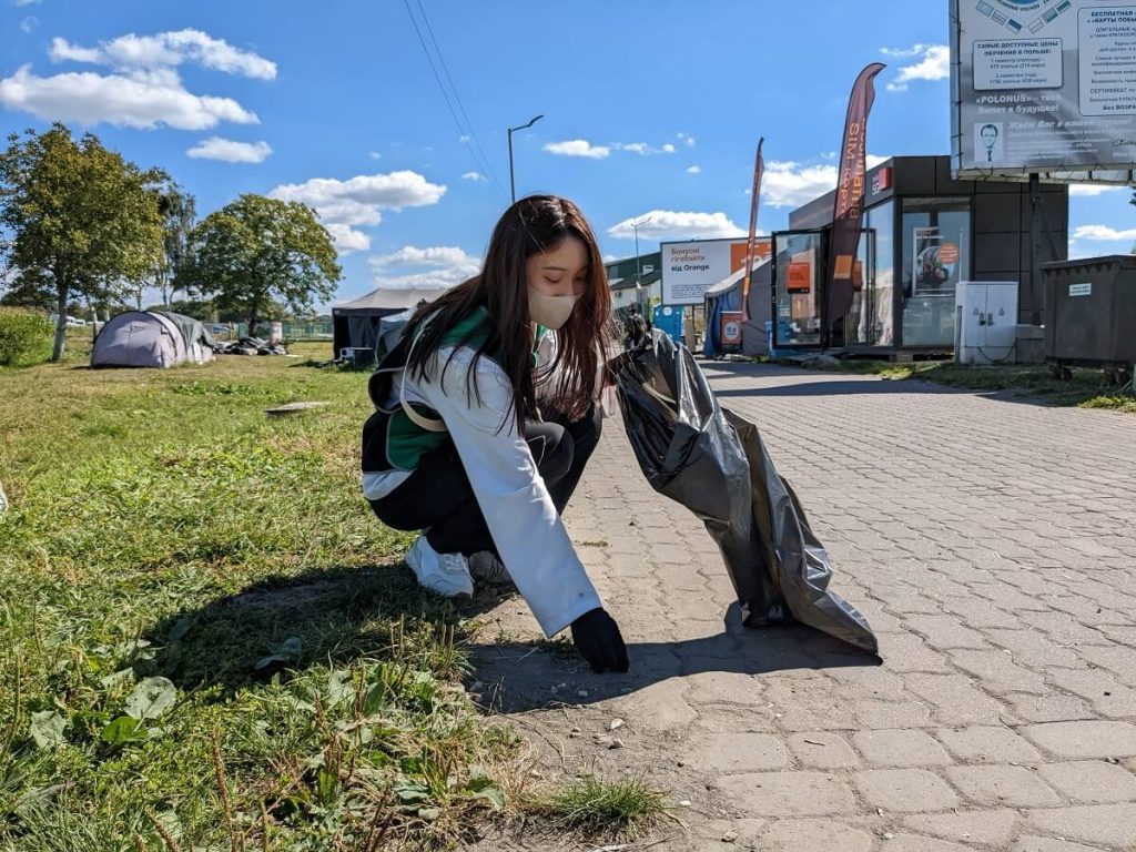 街中でゴミ拾いボランティア活動を行う若い女性の写真