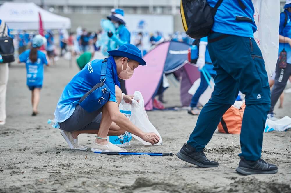 砂浜でゴミを拾うボランティアの男性