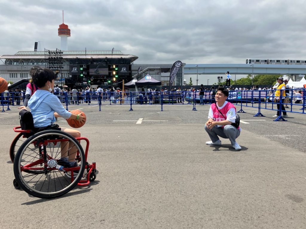 車いすバスケットボールをする少年と向き合うスポーツボランティアの男性