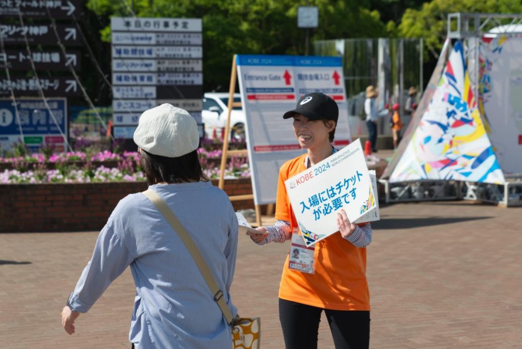 観客に大会パンフレットを配布するボランティア