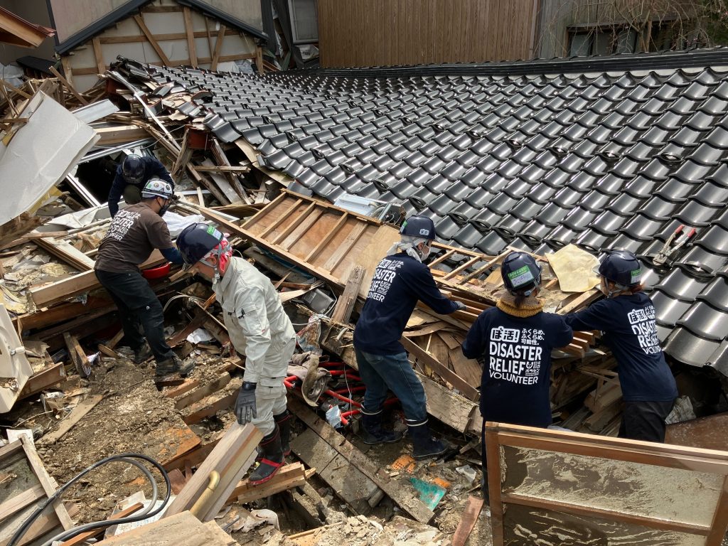 地震の被災地で崩れた家屋から家財を取り出すために瓦礫を片付けるボランティアたちの様子