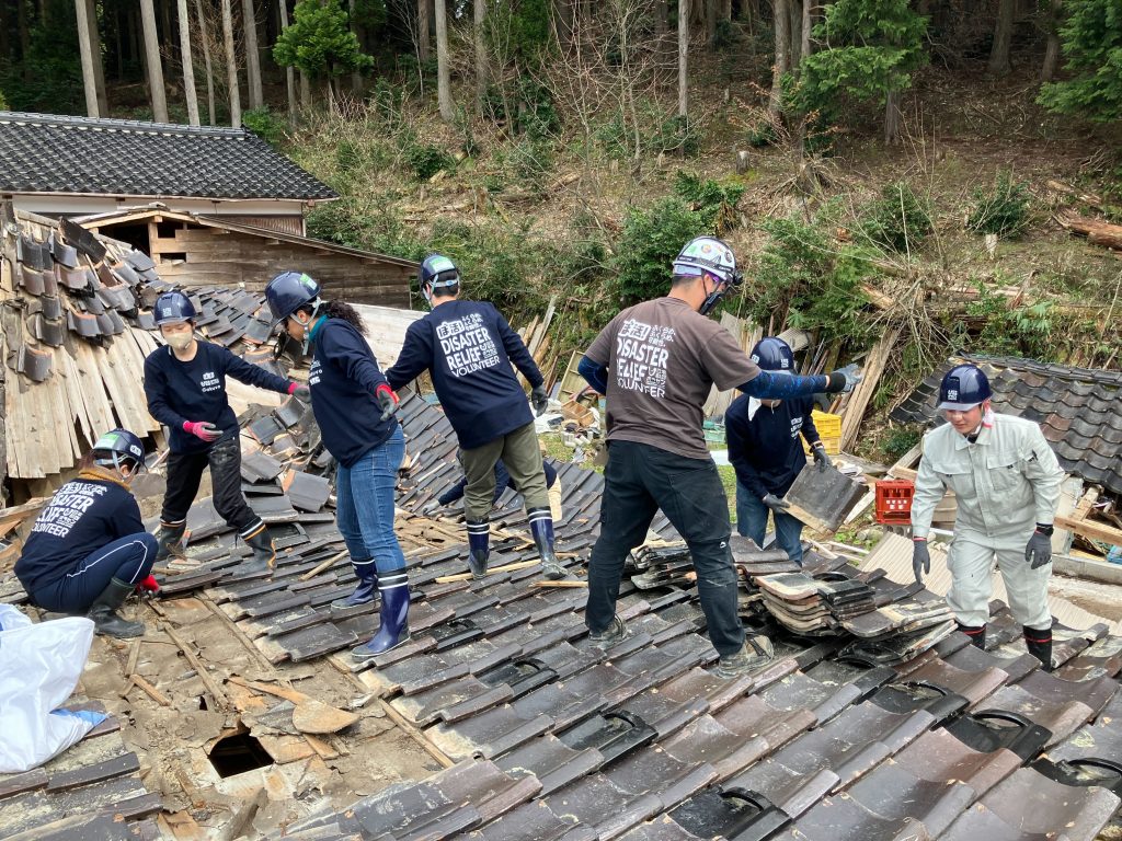 地震の被災地で崩れた家屋の屋根瓦を片付けるボランティアたちの様子