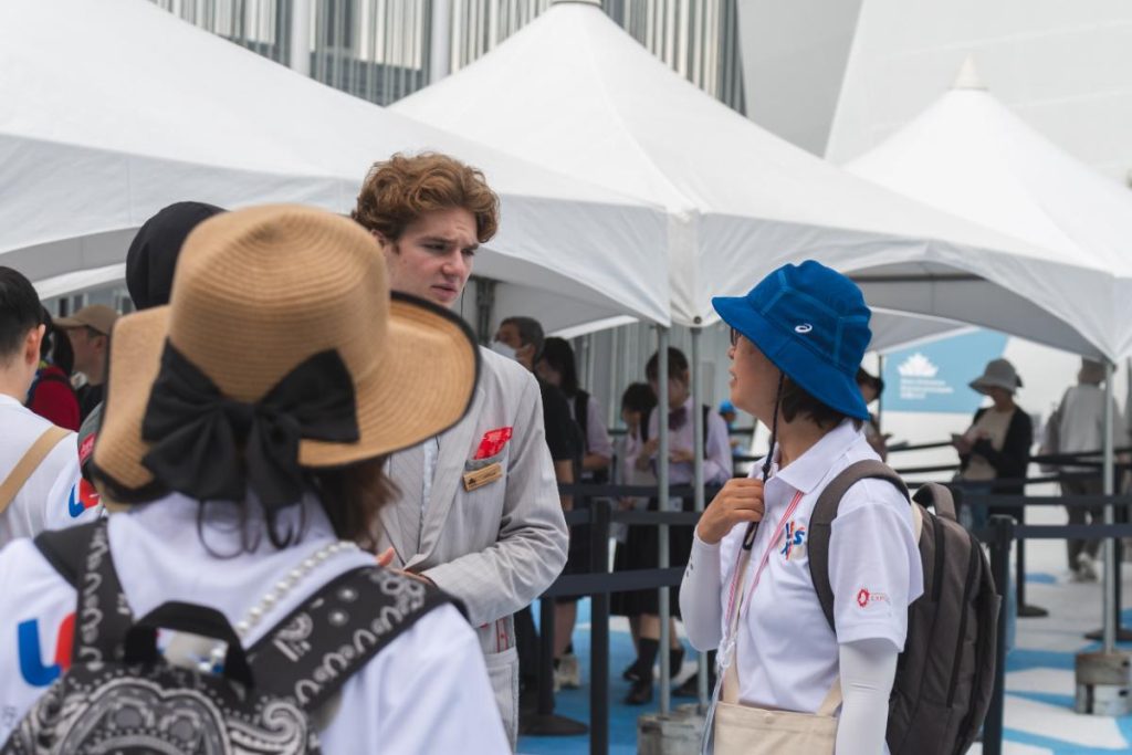 カナダ館パビリオン前で交渉をするLET’S EXPOの会場内サポートボランティア
