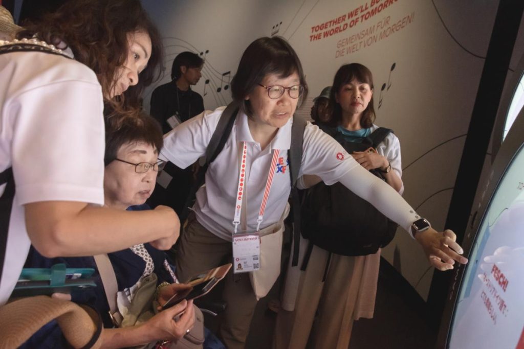 車いすユーザーに説明をする、LET’S EXPOの会場内サポートボランティアの庄司さん