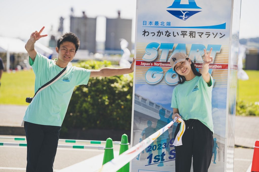 ゴールテープを持つマラソンボランティアたち