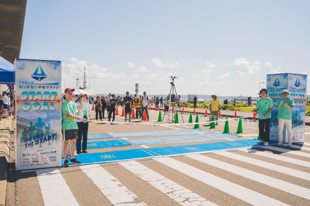 ゴールテープを持ってランナーを待つマラソンボランティア