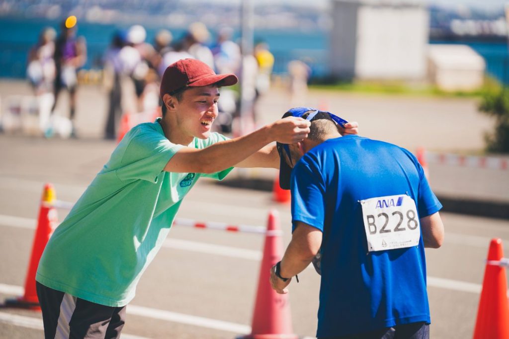 ゴールでランナーにメダルをかけるマラソンボランティア
