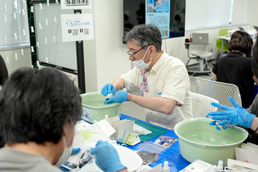 シニアボランティアが被災地支援の一環として写真洗浄を行う様子
