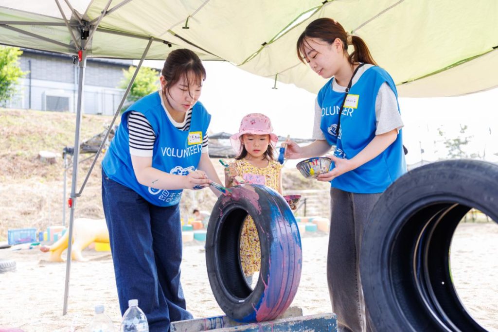 園児と一緒にタイヤにペイントするボランティア