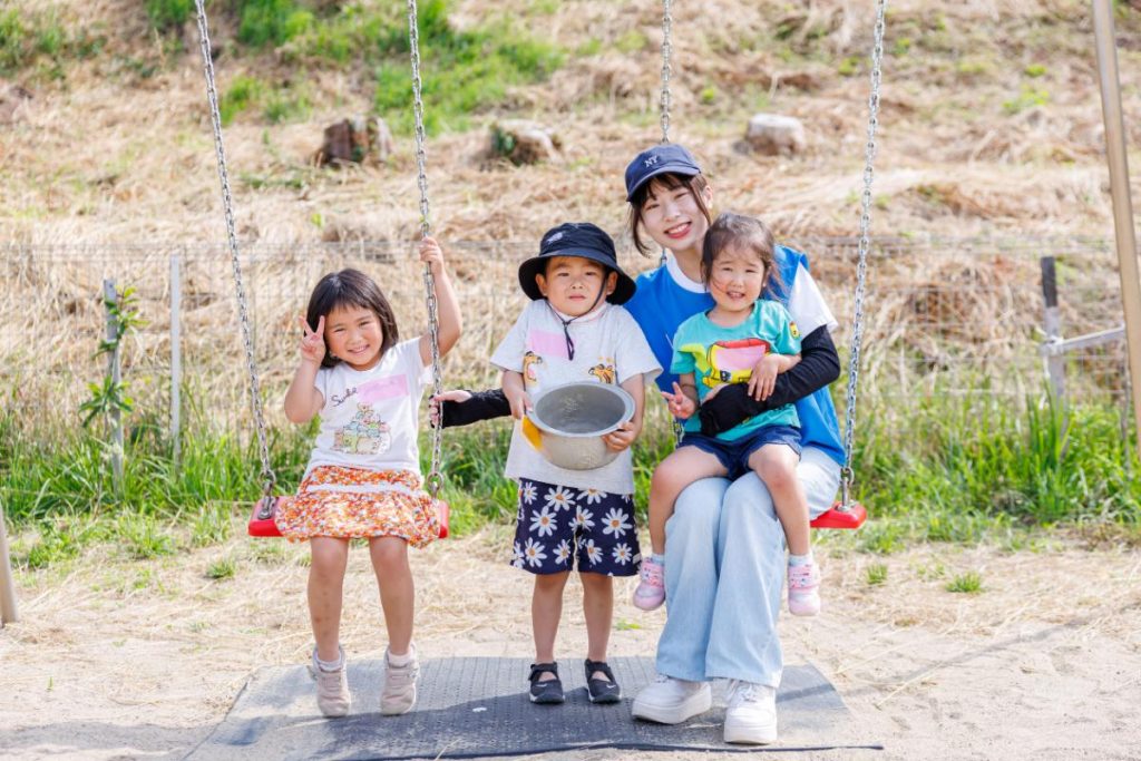 一緒にブランコを漕ぐ園児たちとボランティア
